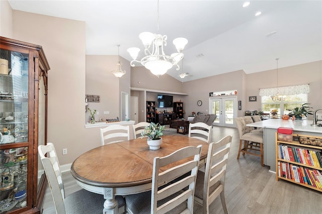 dining room featuring an inviting chandelier, light wood-type flooring, lofted ceiling, and french doors