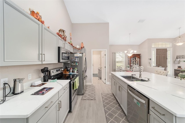 kitchen with pendant lighting, appliances with stainless steel finishes, sink, and light hardwood / wood-style flooring