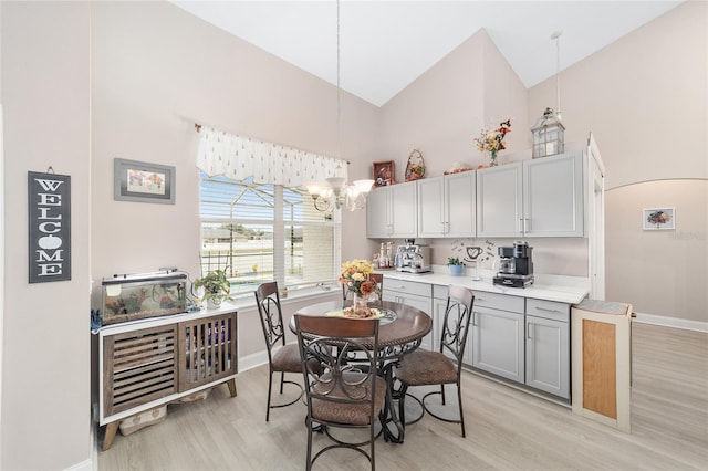 dining area featuring high vaulted ceiling, light hardwood / wood-style flooring, and a notable chandelier