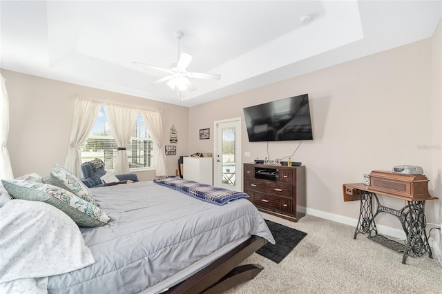 carpeted bedroom with ceiling fan and a raised ceiling