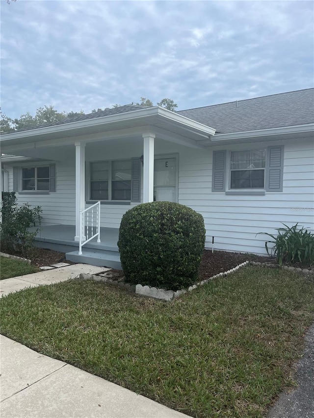 exterior space featuring covered porch and a front yard