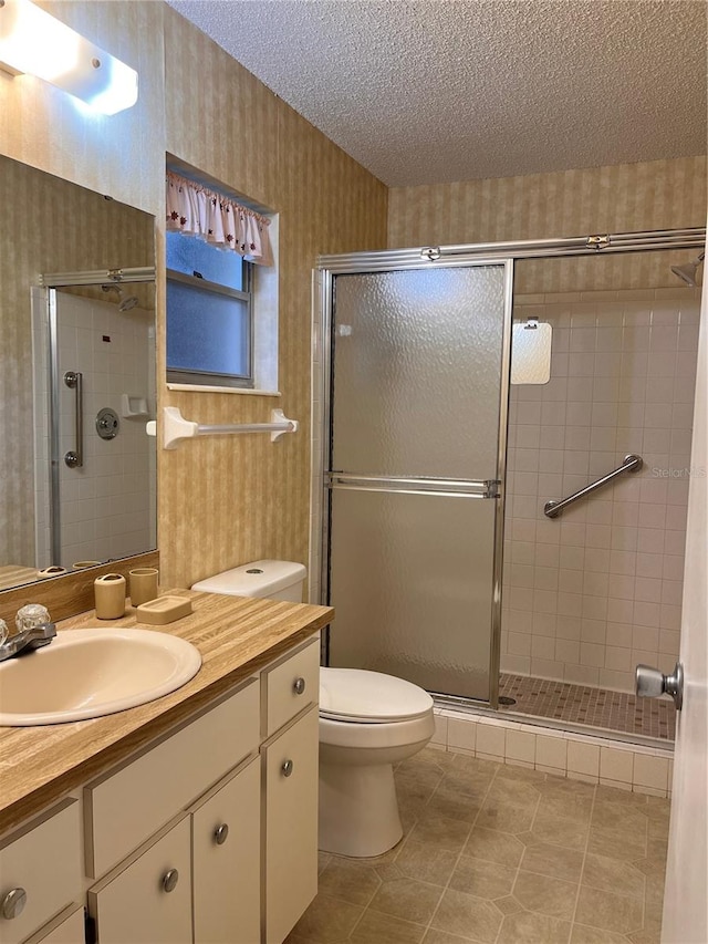 bathroom with tile patterned floors, walk in shower, vanity, a textured ceiling, and toilet