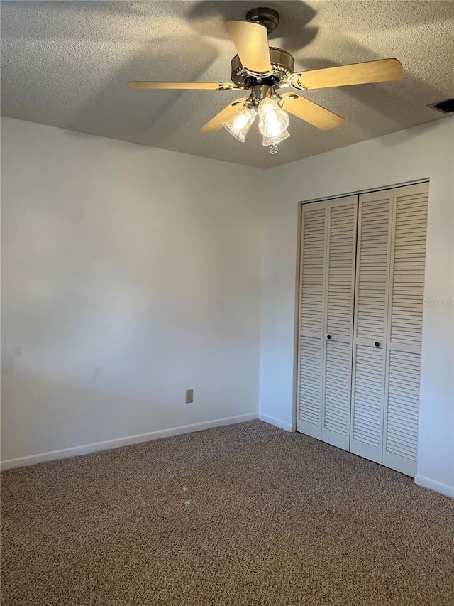 unfurnished bedroom with a textured ceiling, carpet flooring, ceiling fan, and a closet