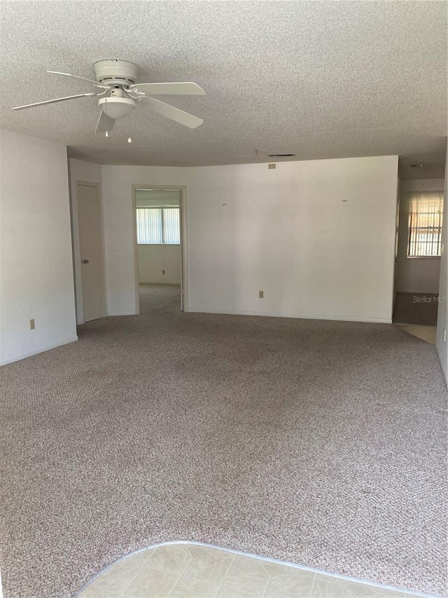 spare room with a textured ceiling, light carpet, and ceiling fan