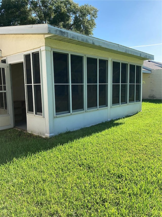 view of side of property with a lawn and a sunroom