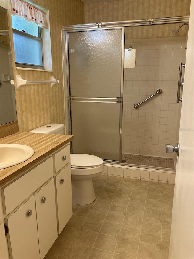 bathroom featuring a shower with door, vanity, toilet, and tile patterned flooring