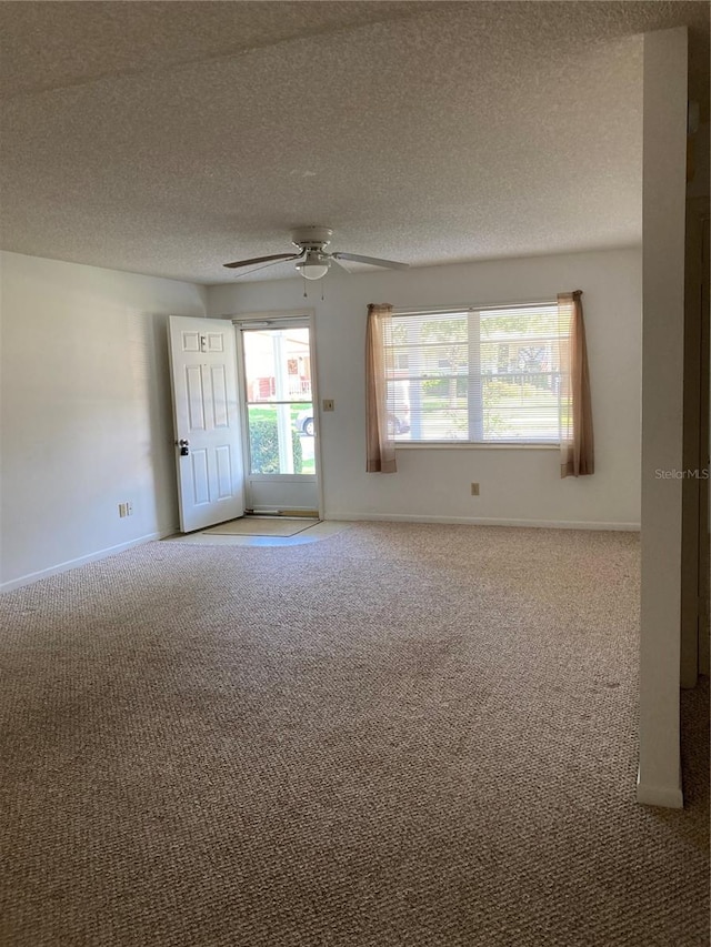 empty room with ceiling fan, a textured ceiling, and carpet