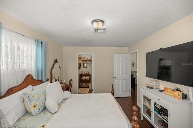 bedroom featuring a spacious closet, a textured ceiling, a closet, and dark hardwood / wood-style flooring