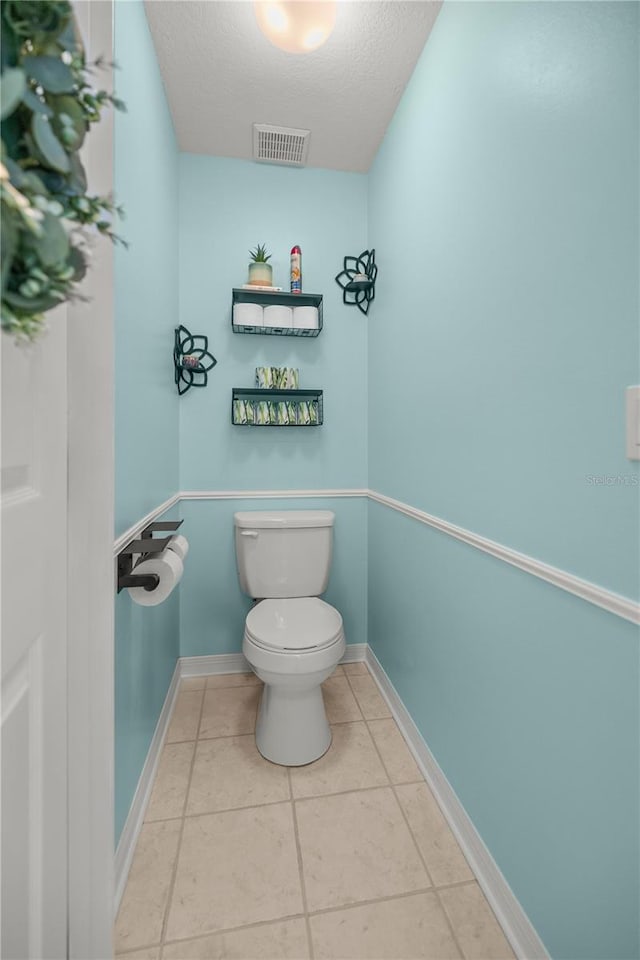 bathroom with toilet, a textured ceiling, and tile patterned flooring