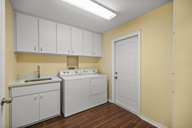 laundry room with washer and clothes dryer, cabinets, sink, and dark hardwood / wood-style floors