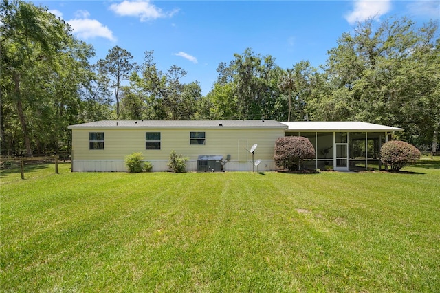 back of property with central air condition unit, a lawn, and a sunroom