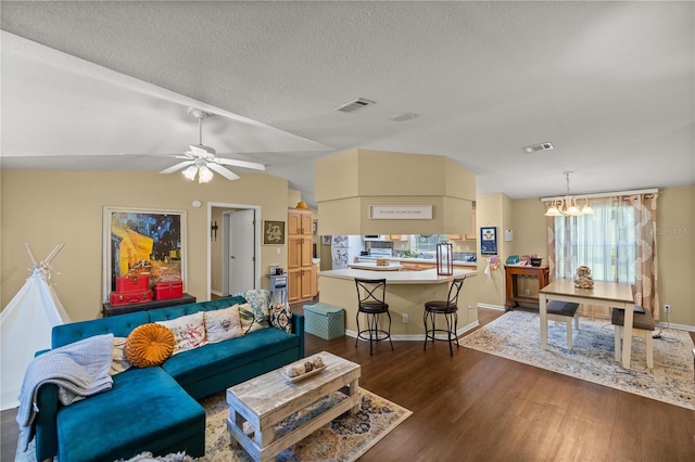 living room featuring dark wood-type flooring, lofted ceiling, a textured ceiling, and plenty of natural light