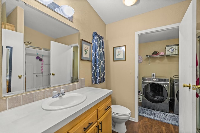 bathroom with walk in shower, hardwood / wood-style flooring, vanity, washing machine and dryer, and toilet