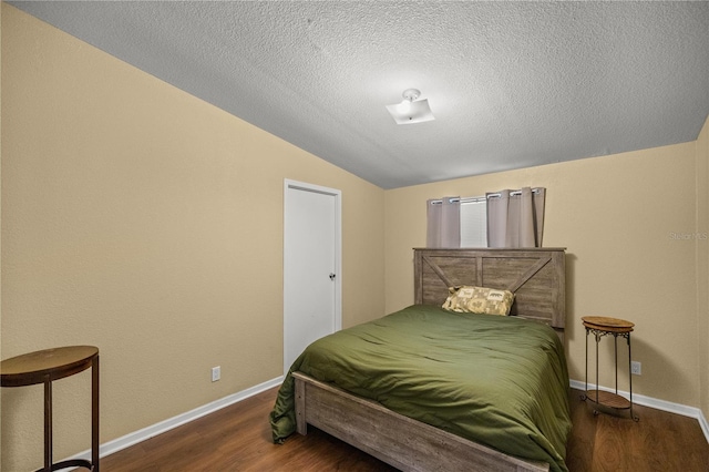 bedroom with dark hardwood / wood-style flooring, a textured ceiling, and lofted ceiling