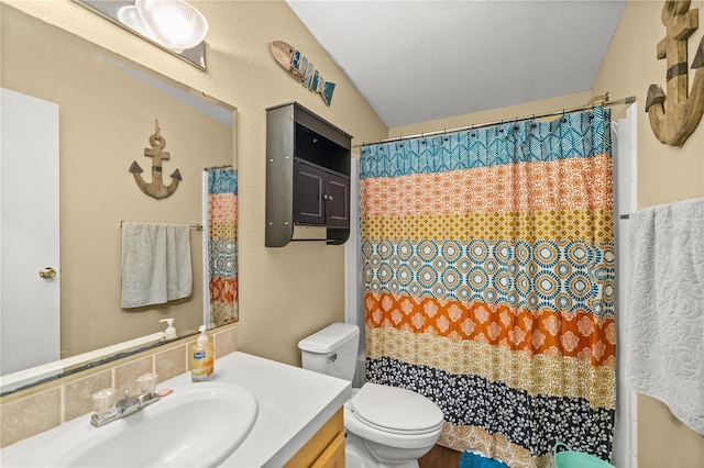 bathroom featuring vanity, a textured ceiling, toilet, and vaulted ceiling