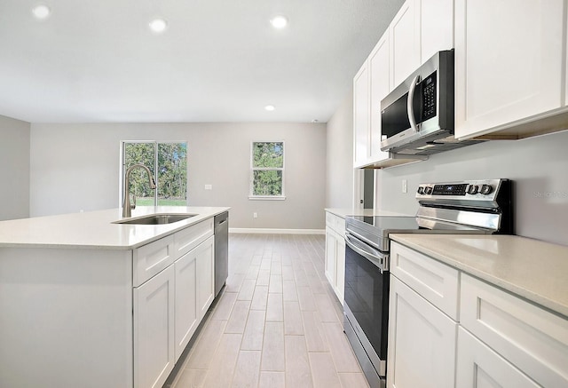 kitchen with sink, light hardwood / wood-style flooring, an island with sink, appliances with stainless steel finishes, and white cabinetry