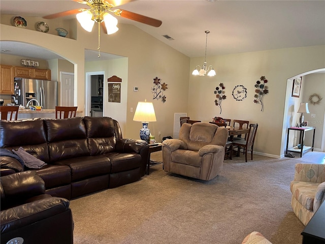 carpeted living room featuring ceiling fan with notable chandelier and vaulted ceiling