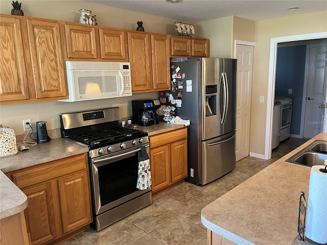 kitchen featuring stainless steel appliances, washer and dryer, light tile patterned floors, and sink