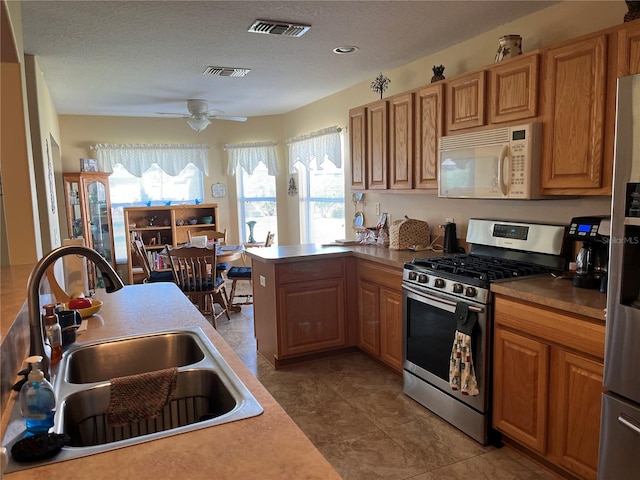 kitchen with a textured ceiling, appliances with stainless steel finishes, sink, and plenty of natural light