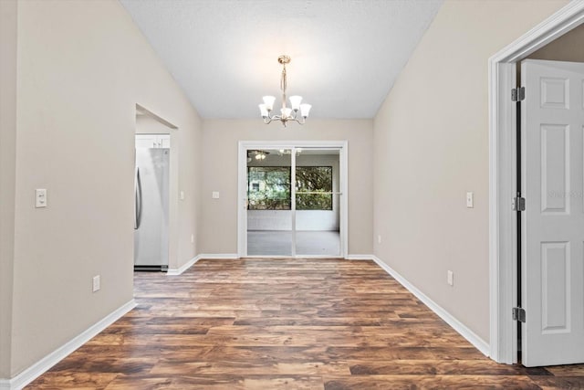 unfurnished dining area with dark hardwood / wood-style flooring, a textured ceiling, vaulted ceiling, and an inviting chandelier