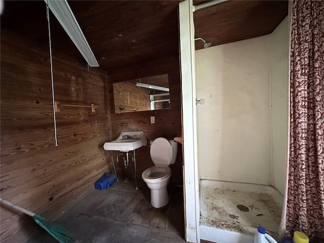 bathroom featuring walk in shower, wood walls, and toilet