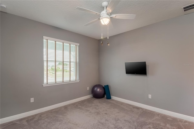 exercise room featuring a textured ceiling, light carpet, and ceiling fan