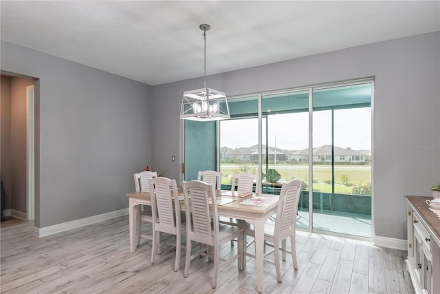 dining area featuring light wood-type flooring, a notable chandelier, and a textured ceiling