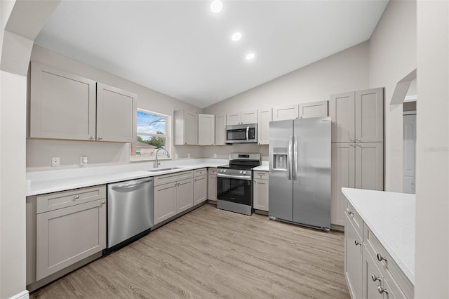 kitchen with gray cabinetry, sink, stainless steel appliances, light hardwood / wood-style floors, and vaulted ceiling