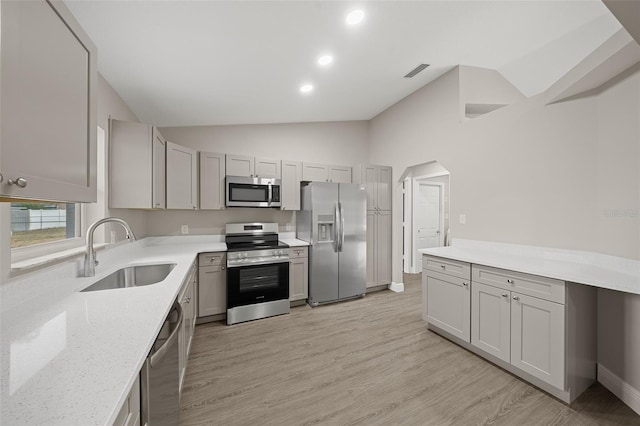 kitchen featuring light wood-type flooring, stainless steel appliances, lofted ceiling, and sink