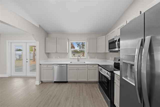 kitchen featuring french doors, sink, vaulted ceiling, light hardwood / wood-style floors, and stainless steel appliances