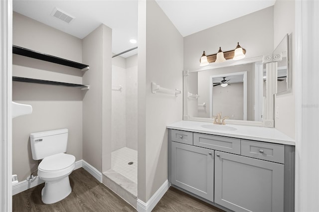 bathroom featuring vanity, ceiling fan, tiled shower, hardwood / wood-style flooring, and toilet