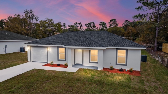 back house at dusk featuring a garage and a yard