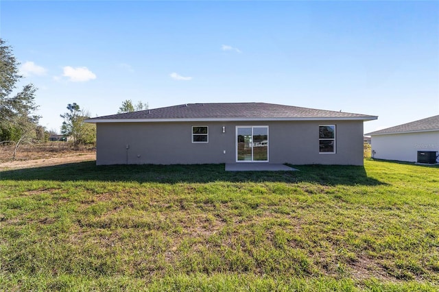 back of house featuring stucco siding, a lawn, and central air condition unit