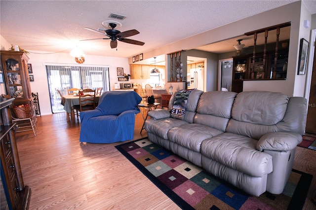 living room featuring ceiling fan, hardwood / wood-style floors, and a textured ceiling