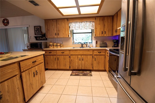 kitchen with light tile patterned floors, sink, appliances with stainless steel finishes, and backsplash