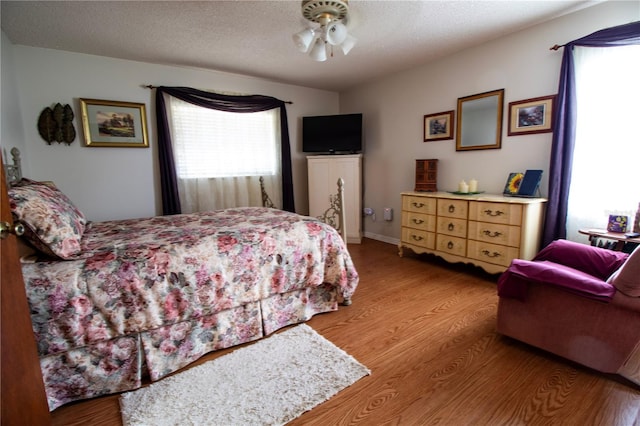 bedroom featuring ceiling fan, hardwood / wood-style floors, and a textured ceiling