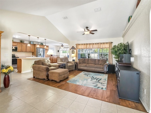 living room with ceiling fan, vaulted ceiling, sink, and light hardwood / wood-style flooring