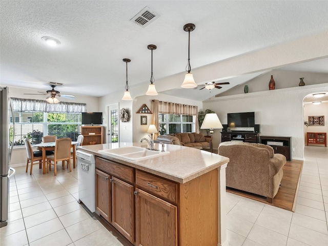 kitchen featuring sink, hanging light fixtures, an island with sink, white dishwasher, and lofted ceiling