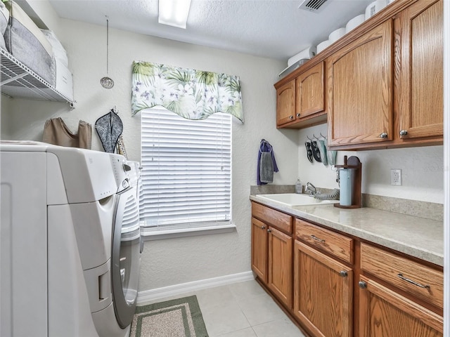 kitchen with sink, hanging light fixtures, a textured ceiling, light tile patterned floors, and washer and dryer