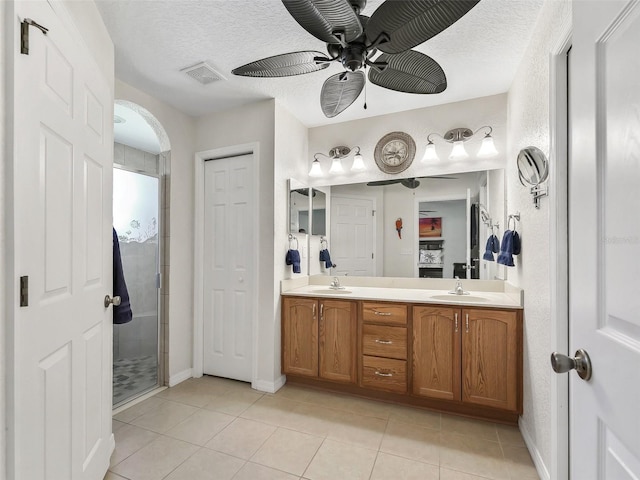 bathroom with tile patterned flooring, vanity, a shower with shower door, and a textured ceiling