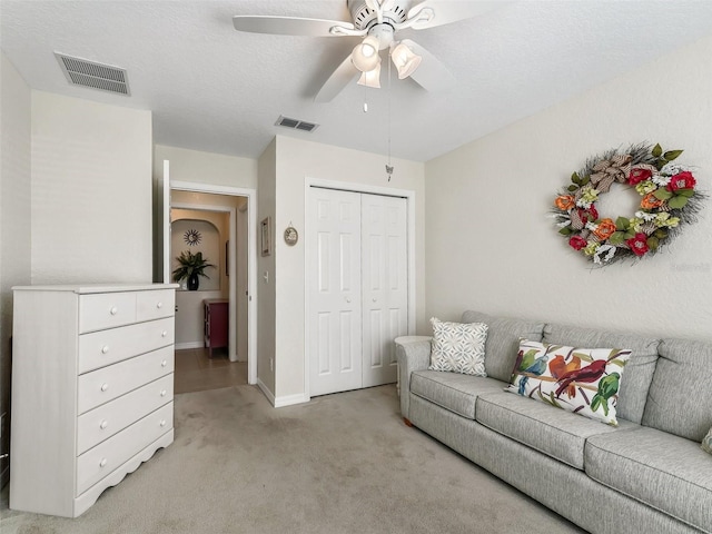 carpeted living room with ceiling fan and a textured ceiling