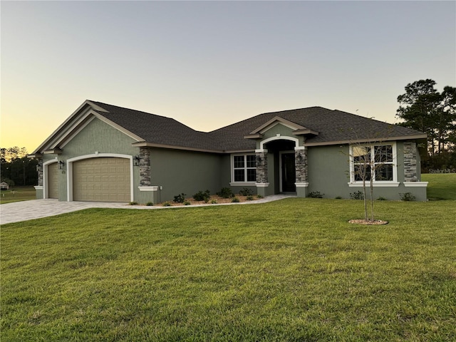 single story home featuring a garage and a lawn