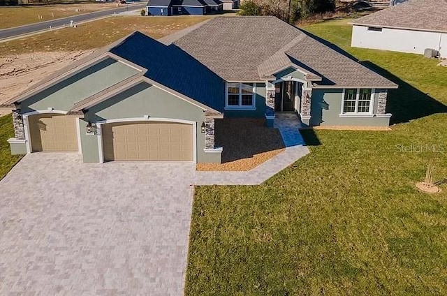 view of front of home with a front lawn, decorative driveway, an attached garage, and stucco siding