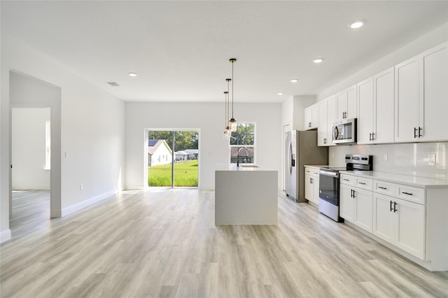 kitchen featuring white cabinetry, stainless steel appliances, light hardwood / wood-style floors, and decorative light fixtures