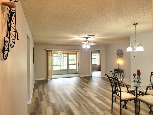 dining room with a textured ceiling, wood-type flooring, and ceiling fan with notable chandelier