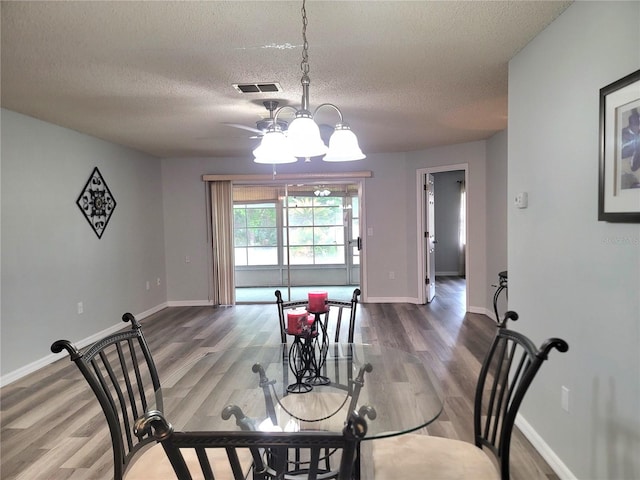 dining space with hardwood / wood-style floors, a textured ceiling, and a chandelier