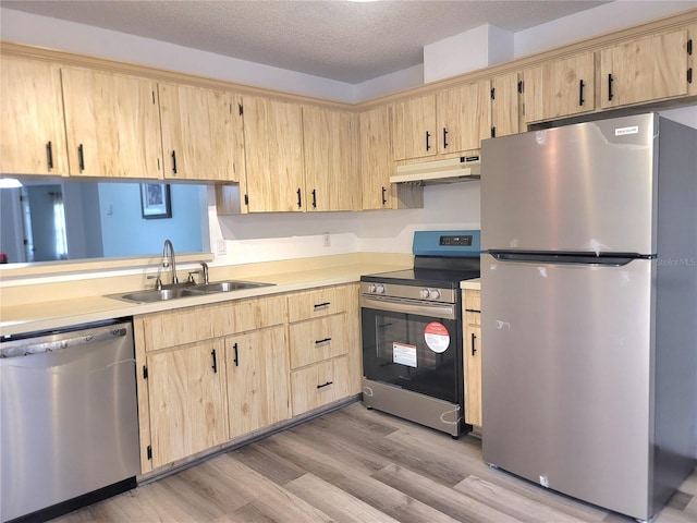 kitchen featuring stainless steel appliances, sink, light brown cabinets, a textured ceiling, and light hardwood / wood-style flooring