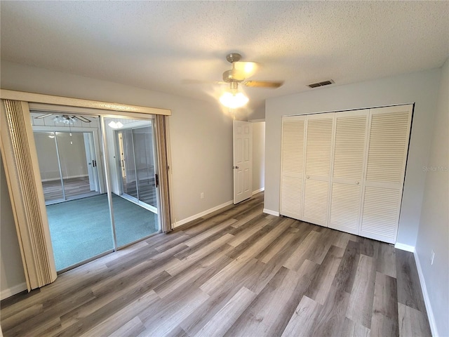 unfurnished bedroom with hardwood / wood-style flooring, ceiling fan, and a textured ceiling