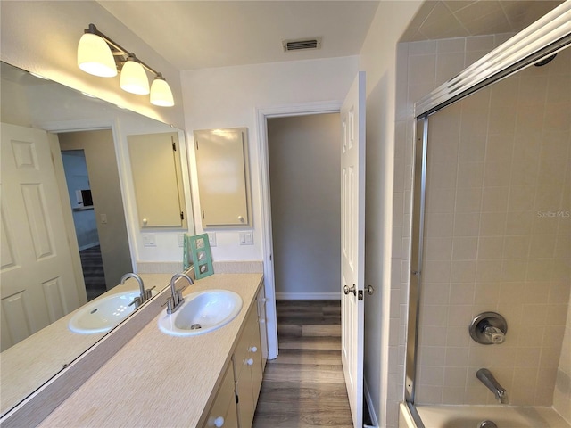 bathroom with hardwood / wood-style floors, tiled shower / bath, and vanity