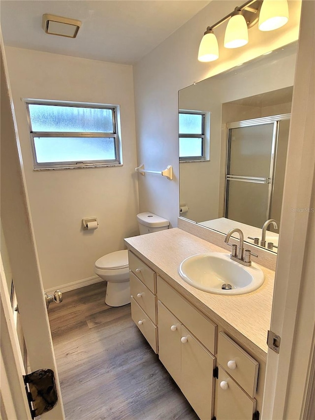 bathroom with hardwood / wood-style floors, vanity, a healthy amount of sunlight, and toilet